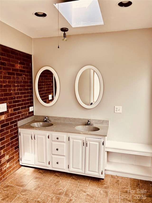 bathroom with brick wall, double vanity, a skylight, and a sink