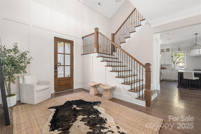 foyer entrance featuring visible vents, dark wood-style floors, a high ceiling, crown molding, and stairs