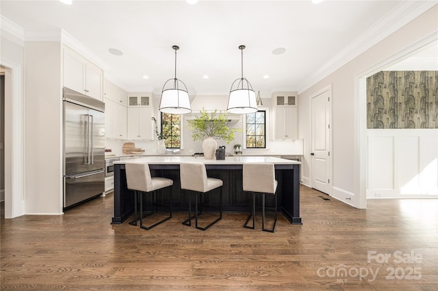 kitchen featuring a kitchen island, glass insert cabinets, light countertops, stainless steel built in fridge, and white cabinetry