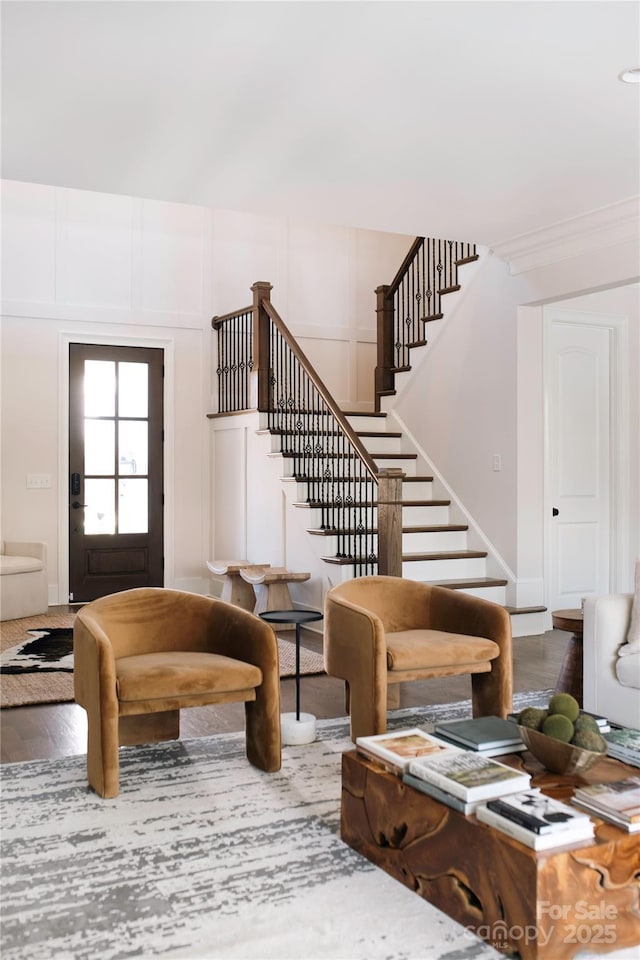 living area featuring stairway, wood finished floors, and a decorative wall