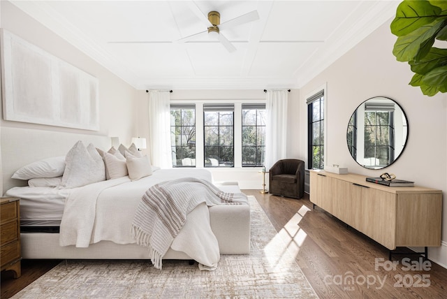 bedroom featuring multiple windows, wood finished floors, a ceiling fan, and ornamental molding