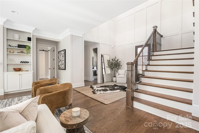 interior space featuring stairs, crown molding, a decorative wall, and wood finished floors