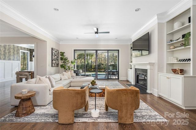 living area with a wealth of natural light, built in shelves, a fireplace, and wood finished floors