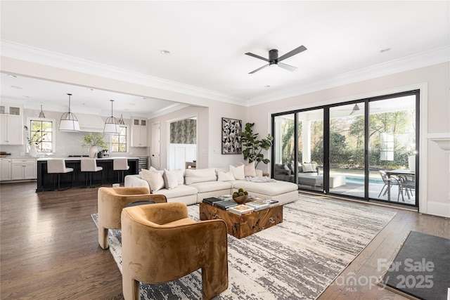 living area with a ceiling fan, wood finished floors, and crown molding