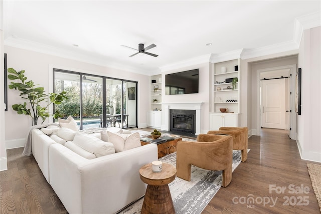 living room with baseboards, a fireplace with flush hearth, wood finished floors, and crown molding