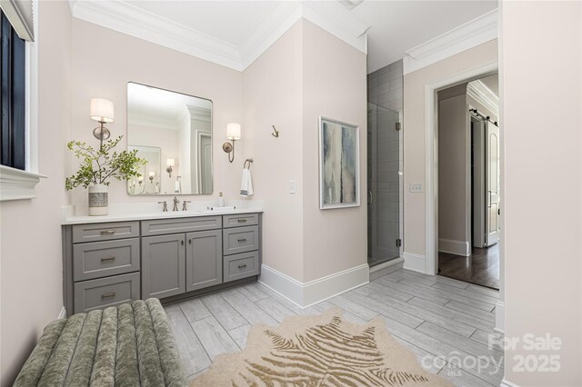 bathroom featuring wood tiled floor, a stall shower, ornamental molding, baseboards, and vanity