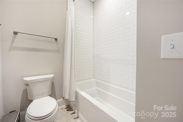 bathroom featuring shower / bathtub combination with curtain and toilet