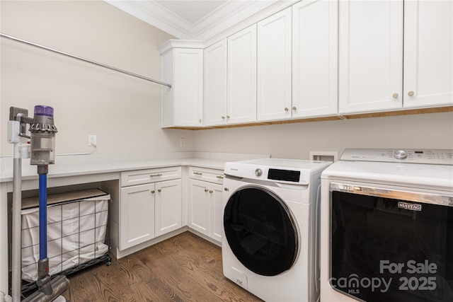 clothes washing area featuring washing machine and clothes dryer, dark wood-style flooring, cabinet space, and ornamental molding