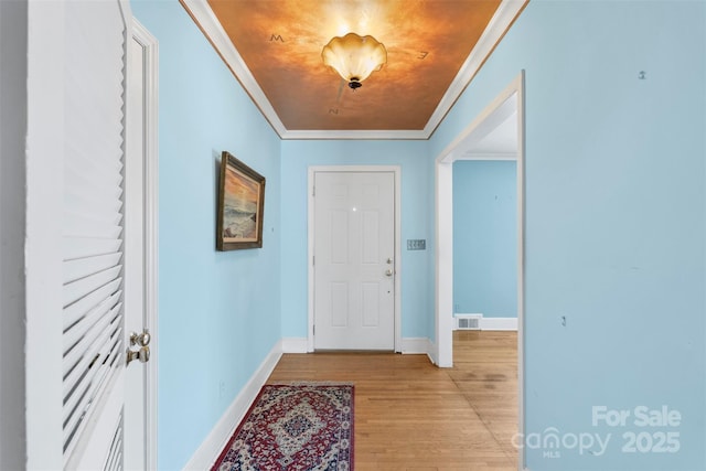 interior space with visible vents, light wood-style flooring, baseboards, and ornamental molding