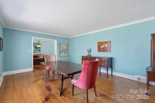 dining space with visible vents, ornamental molding, baseboards, and wood finished floors