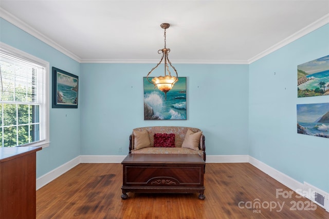 living area featuring baseboards, wood finished floors, and crown molding