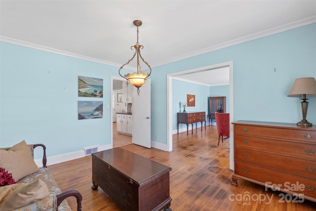 living area featuring crown molding, baseboards, and wood finished floors