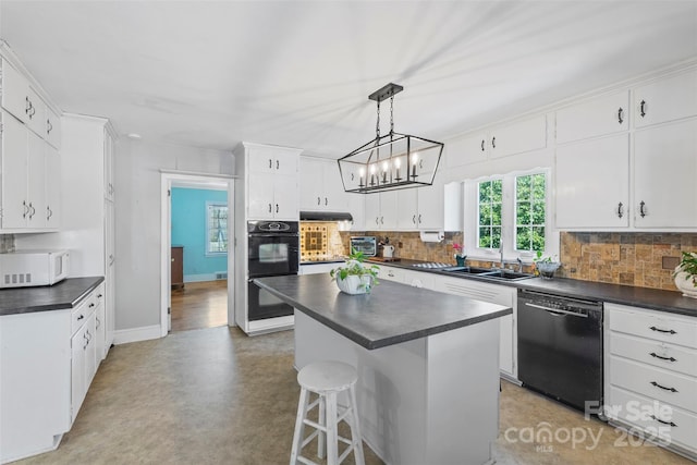 kitchen with dark countertops, decorative backsplash, black appliances, and a sink