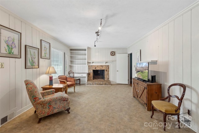 sitting room featuring visible vents, ornamental molding, built in features, a fireplace, and light colored carpet