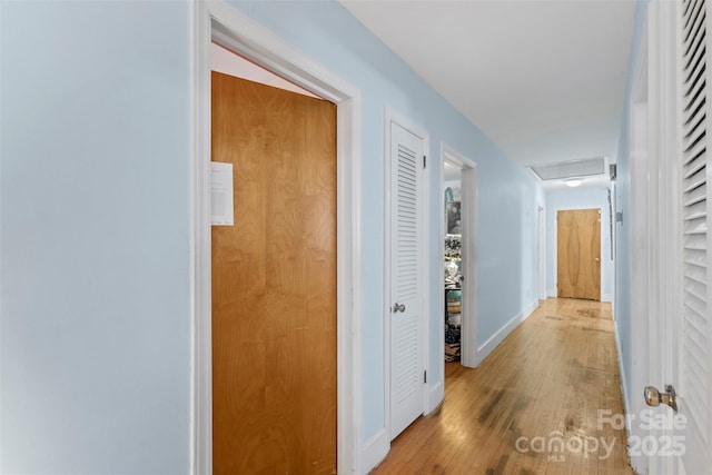 hallway featuring baseboards, attic access, and wood finished floors