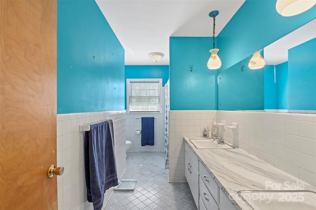 bathroom with tile patterned flooring, toilet, tile walls, and a sink