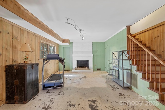 exercise area with visible vents, wooden walls, a fireplace, and crown molding