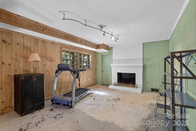 exercise area featuring visible vents, wood walls, a fireplace, and crown molding