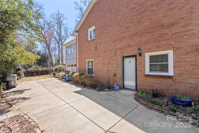 exterior space featuring a garage, brick siding, a patio area, and fence