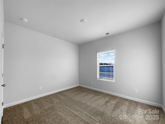 empty room featuring baseboards, visible vents, and carpet flooring