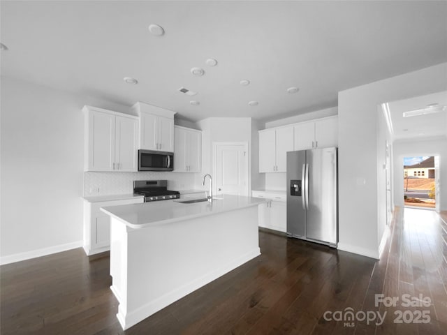 kitchen with appliances with stainless steel finishes, dark wood-style flooring, a sink, and an island with sink