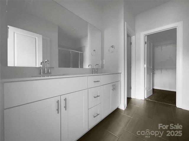 full bath with double vanity, a stall shower, a sink, and tile patterned floors