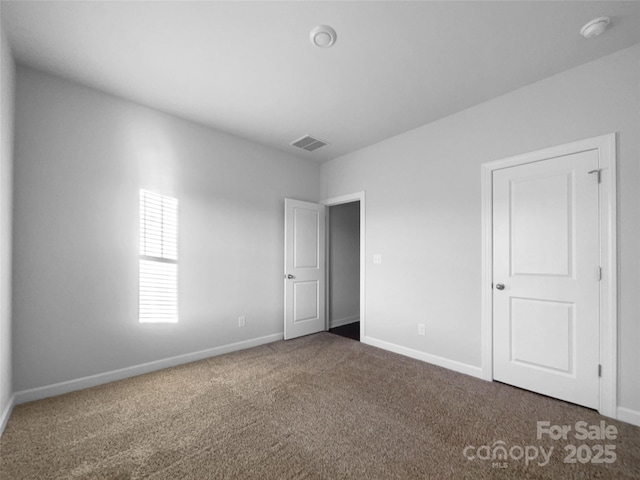 unfurnished bedroom with carpet floors, visible vents, and baseboards