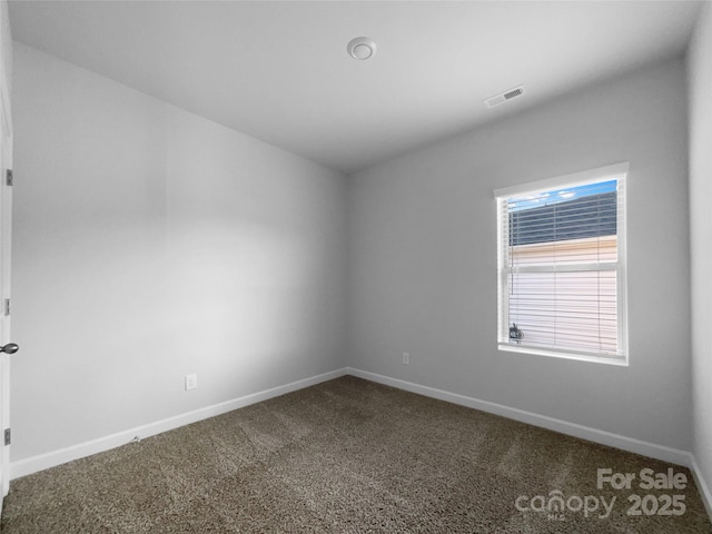 unfurnished room featuring dark carpet, visible vents, and baseboards