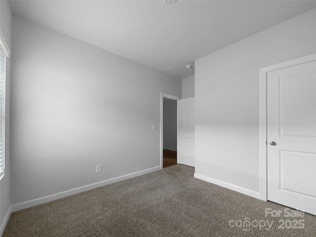 unfurnished bedroom with dark colored carpet and baseboards