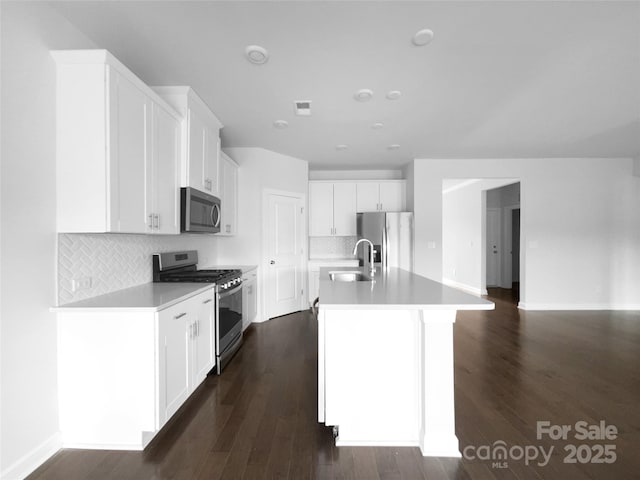 kitchen featuring light countertops, appliances with stainless steel finishes, a sink, and dark wood finished floors