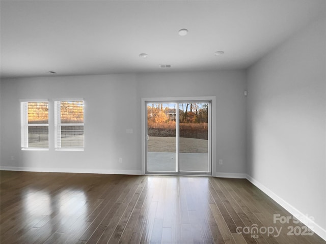 unfurnished room featuring dark wood-style floors, visible vents, and baseboards