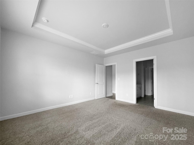 unfurnished bedroom with baseboards, a tray ceiling, and carpet flooring