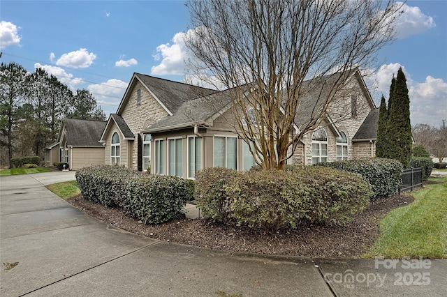 view of home's exterior featuring stone siding and driveway