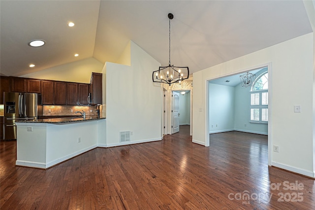 kitchen featuring dark brown cabinetry, tasteful backsplash, stainless steel fridge, visible vents, and dark wood finished floors