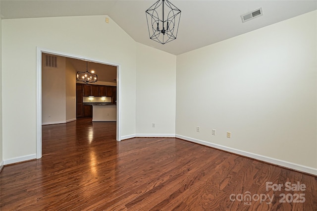 spare room with a chandelier, visible vents, baseboards, and dark wood-style floors