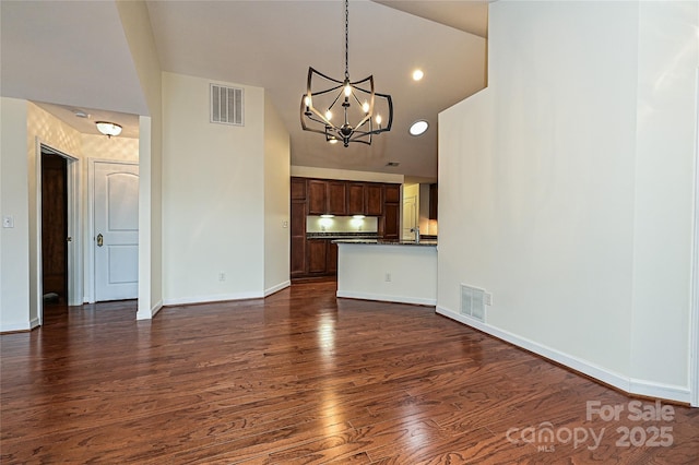 unfurnished living room featuring baseboards, dark wood-style flooring, visible vents, and a notable chandelier