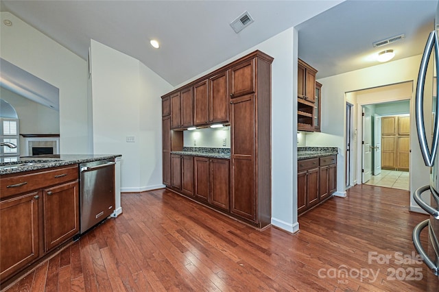 kitchen featuring dark wood finished floors, visible vents, a tiled fireplace, appliances with stainless steel finishes, and dark stone counters