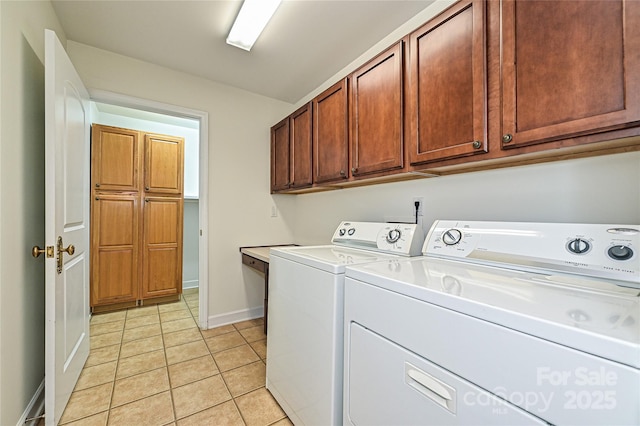 washroom with cabinet space, light tile patterned floors, baseboards, and washing machine and clothes dryer