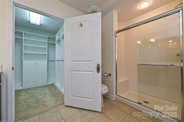 full bathroom with a stall shower, toilet, and tile patterned floors