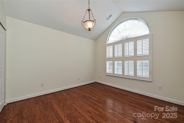 empty room with dark wood-style floors, vaulted ceiling, visible vents, and plenty of natural light