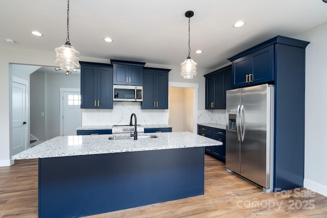 kitchen featuring appliances with stainless steel finishes, blue cabinets, a sink, and light stone counters