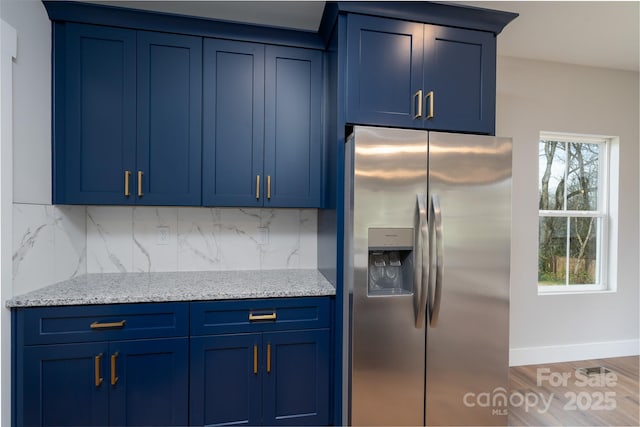 kitchen with blue cabinets, stainless steel fridge, and backsplash