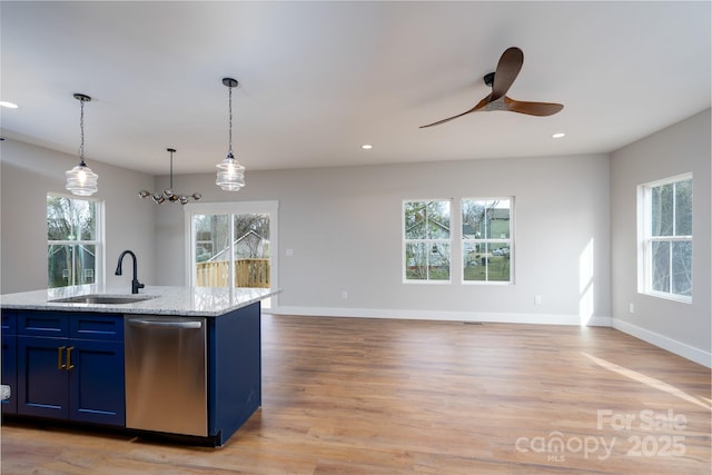 kitchen featuring light wood finished floors, recessed lighting, stainless steel dishwasher, open floor plan, and a sink