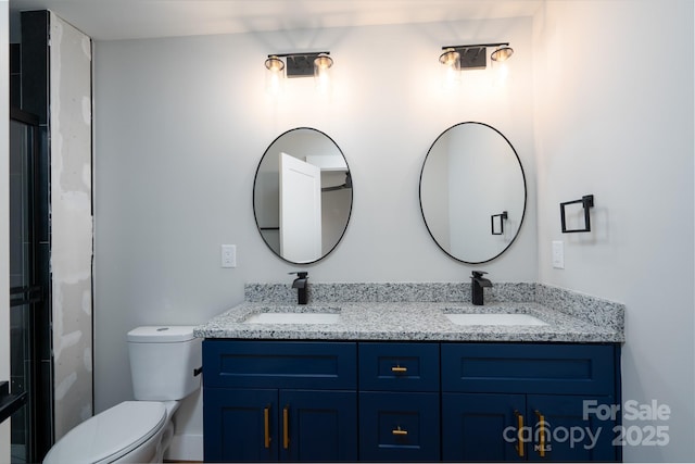 full bath with toilet, double vanity, and a sink