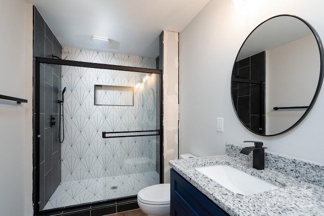 bathroom featuring toilet, a shower stall, and vanity