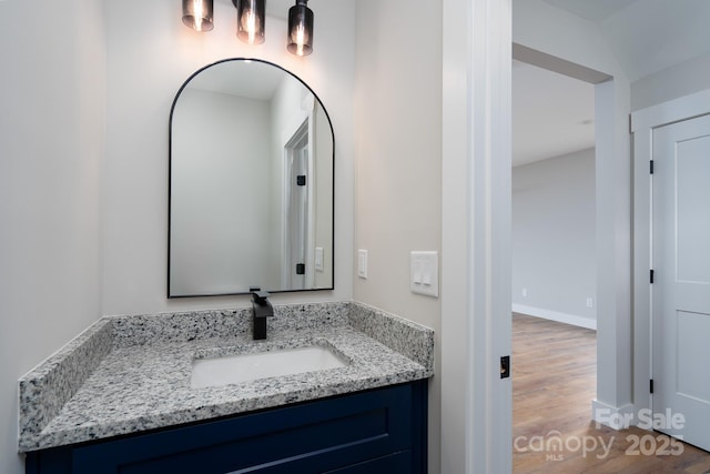 bathroom featuring baseboards, wood finished floors, and vanity