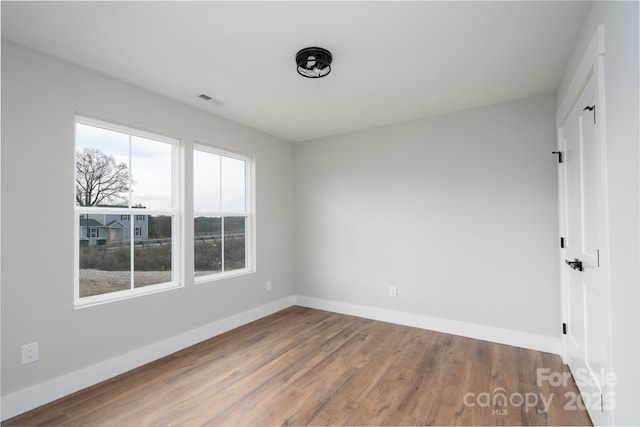 unfurnished room with visible vents, baseboards, and wood finished floors