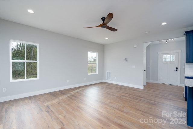 spare room featuring light wood-type flooring, plenty of natural light, and visible vents