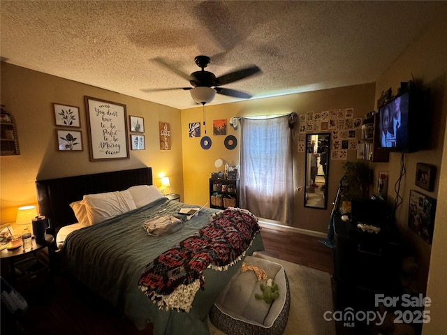 bedroom with ceiling fan, wood finished floors, and a textured ceiling