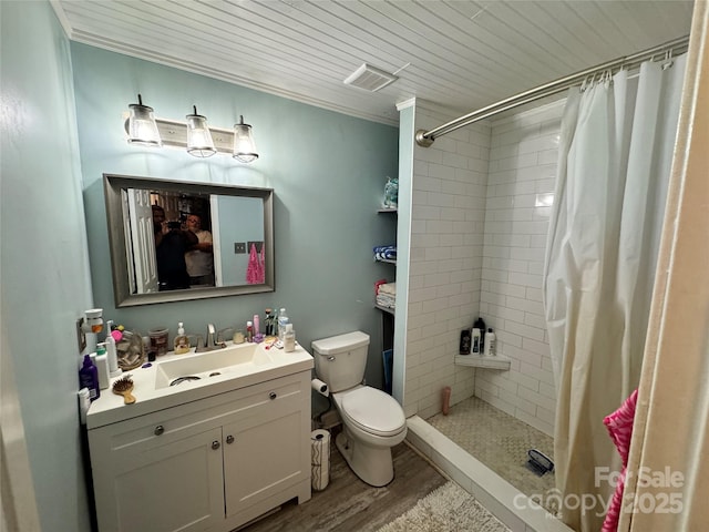 full bath featuring visible vents, toilet, wood finished floors, tiled shower, and vanity